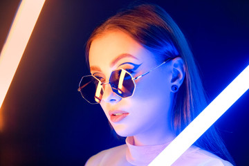 Toned portrait of beautiful woman with neon lamps on dark background