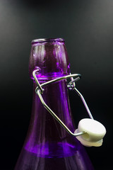  glass purple bottle with stopper isolated on a black background