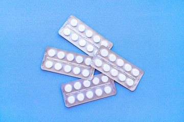 Aspirin in a blister on top. Vitamin C pills in a pack. White tablets in a blister on a blue background close-up with soft focus. 