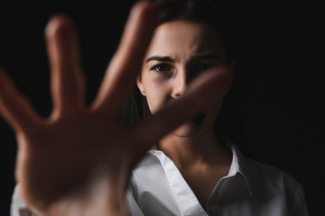 Scared female victim with taped mouth on dark background. Concept of violence