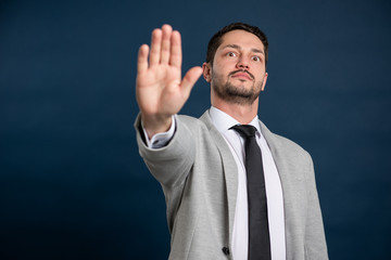 Portrait of business young handsome male showing stop gesture