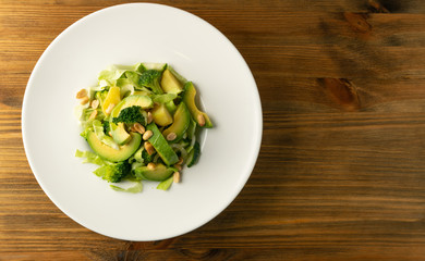Green Salad with Avocado, Cucumber and Nuts on White Plate