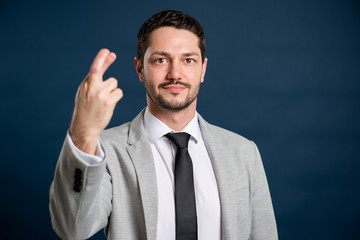 Portrait of business young handsome male showing fingers crossed