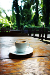 white mug with coffee on a wooden table in a coffee shop on the street