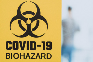 Yellow biohazard warning sign attached on glass of door