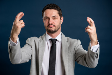 Portrait of business young handsome male showing fingers crossed