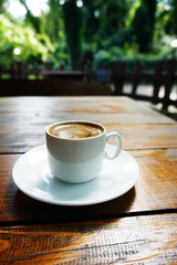 white mug with coffee on a wooden table in a coffee shop on the street