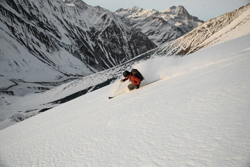 Naklejka na ściany i meble man performs freeride skiing on snow-capped mountains.