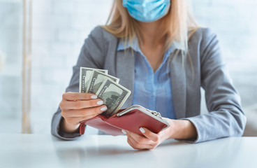 Woman in protective mask puts dollars in wallet