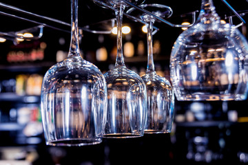 Wine and martini glasses in shelf above a bar rack in restaurant. 