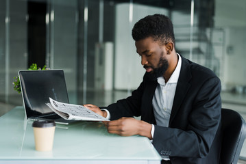 Young African man reading news in the morning in office