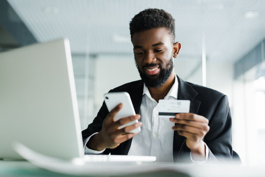 African American Man Paying With Credit Card Online While Making Orders Via Mobile Internet Making Transaction Using Mobile Bank Application.