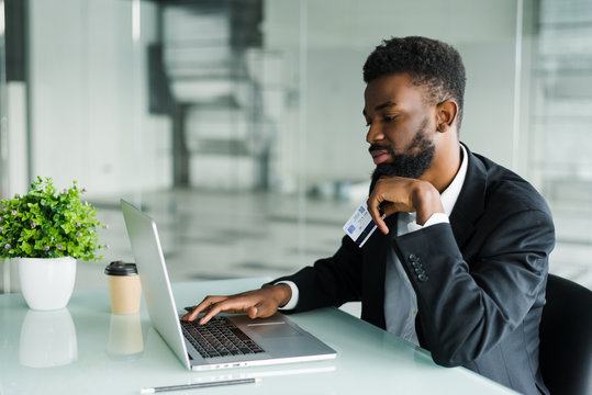 Thoughtful young african american businessman working on laptop in office