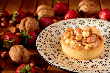 Mini tart cupcake with walnuts, almonds and hazelnuts on plate. Close up