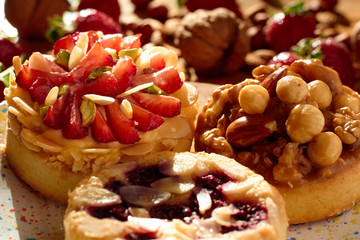 Three mini tarts cupcakes with strawberries, walnuts, almond, nuts and blueberries on plate