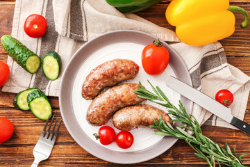 Plate with tasty grilled sausages and vegetables on table