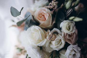 wedding rings on a bouquet of white and pink flowers.