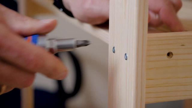 a man screws a shelf. Screw and screwdriver. Male hand. Houseworker. Close-up