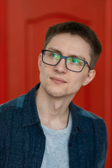 portrait of a cute guy with very bright facial expressions and emotions against a red wall