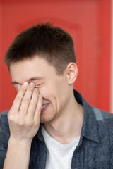 portrait of a cute guy with very bright facial expressions and emotions against a red wall