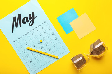 Calendar with stationery and hourglass on color background. Deadline concept