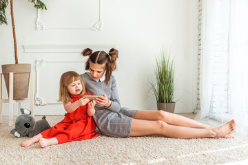 Two sisters play games on phone. anti-communication. They do not know how to communicate, poor communication.girls turned away from each other. do not see, hear each other, understand one of one