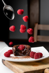French dessert, chocolate volcano or coulant, baked cake with delicious melted chocolate. Various raspberries falling on the plate