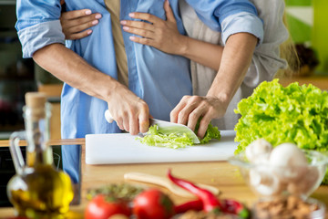 Obraz na płótnie Canvas Unrecognizable husband cooking fresh vitamin salad at home