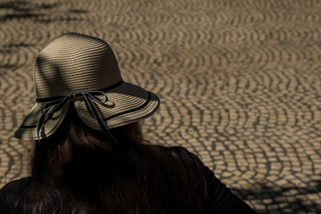 Woman with hat in a shadow on a street. Shallow depth of field