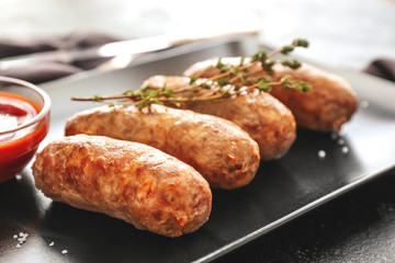 Plate with tasty grilled sausages on table, closeup