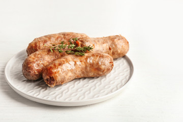 Plate with tasty grilled sausages on table
