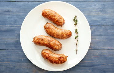Plate with tasty grilled sausages on color wooden background