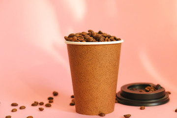 Take away coffee cup full of coffee beans on pink background. Good morning, coffee energy concept.