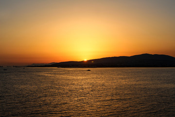 a sunset above the sea in the resort town of Gelendzhik, the sun is gradually left behind mountains. Black sea coast