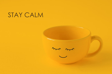 cute yellow cup with eyes and mouth and note stay calm on a yellow background