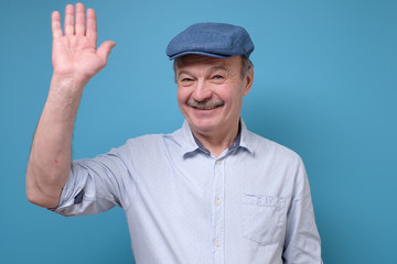 Mature hispanic man waving hand welcoming his friend
