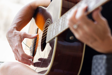 Hands of woman playing acoustic guitar. Focus on guitarist fingers next to sound hole. Music lessons, practice concepts
