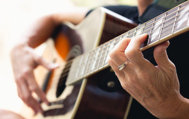 Hands of woman playing acoustic guitar. Focus on fingerboard part. Music lesson concept, vintage effect applied