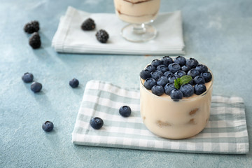 Tasty tiramisu with berries on color background