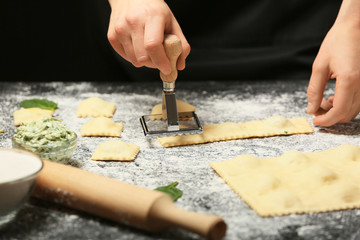 Woman preparing tasty ravioli on table