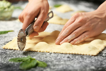 Woman preparing tasty ravioli on table