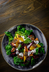 vegetarian salad with beets, spinach, orange, tofu in plate on wooden table background