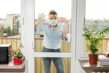 a man in a medical mask and medical gloves with a bouquet stands on the balcony