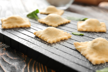 Raw ravioli on wooden board