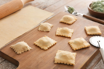 Raw ravioli on wooden board