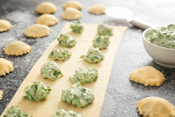 Preparing of tasty ravioli on dark background