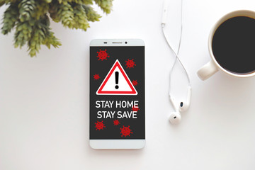 Top view smart phone with text "Stay Home, Stay Safe" on screen.