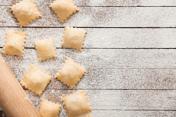 Raw ravioli with rolling pin on table
