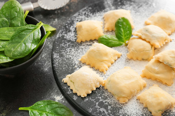 Raw ravioli with spinach on dark background