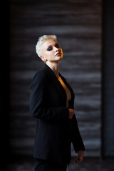 Portrait of blonde girl with a short stylish haircut on a dark background.